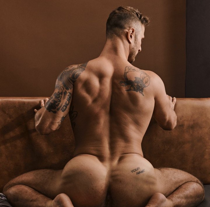 blain o connor sitting naked on brown leather sofa with his back to the camera showing off his thick muscled bubble butt and your name tattoo on right butt cheek