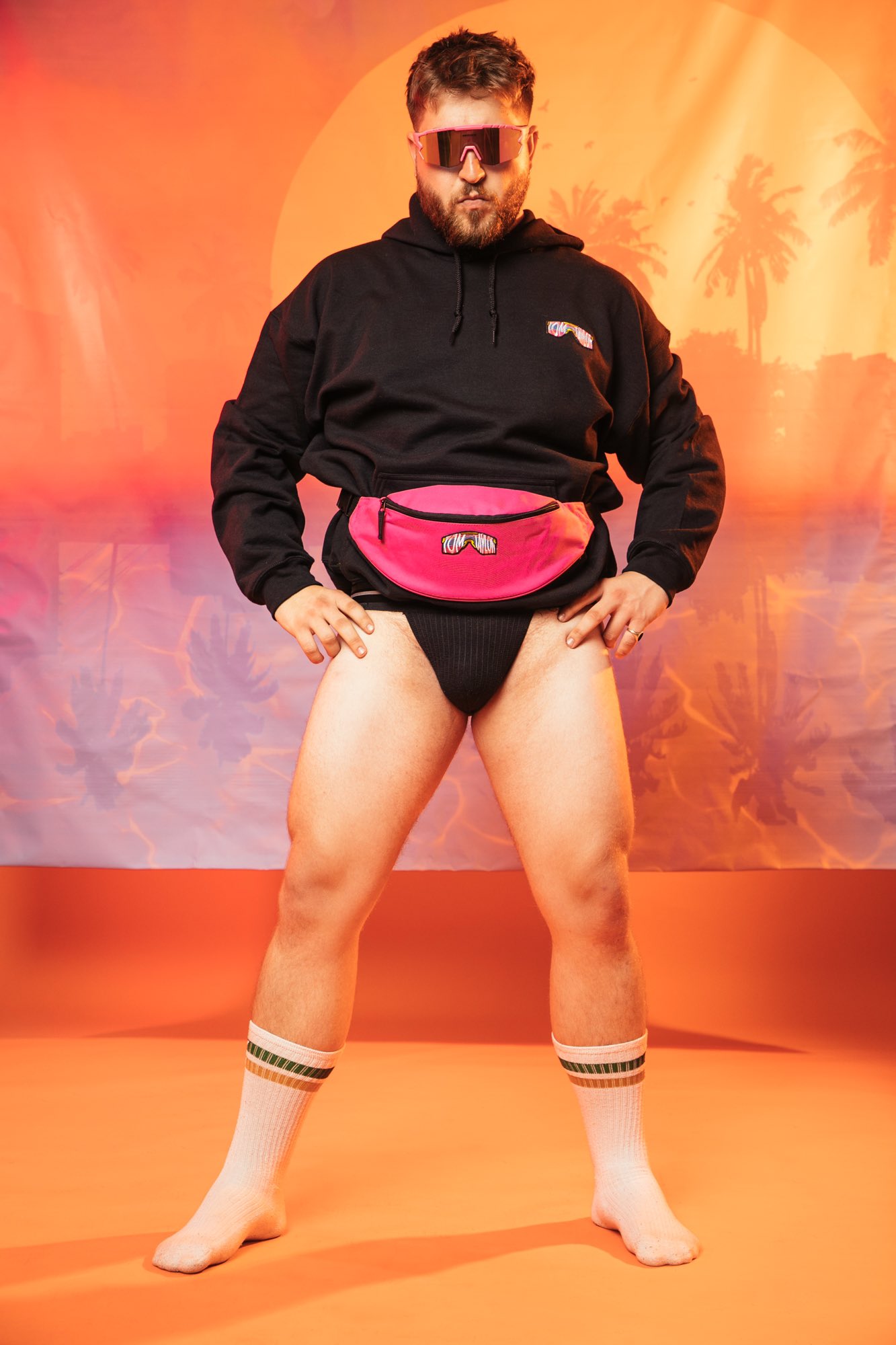 gay male model wearing no pants and a pink fanny pack and hoodie with tom taylor illustrations for promo photoshoot