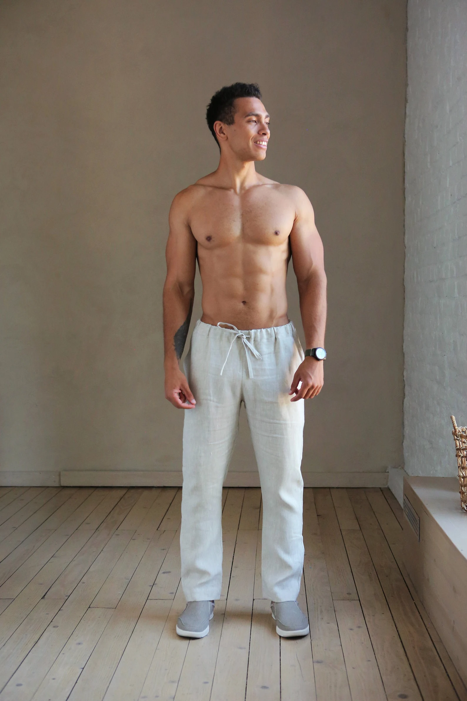 gay male model wearing white linen resort pants in empty room for promotional clothing shot