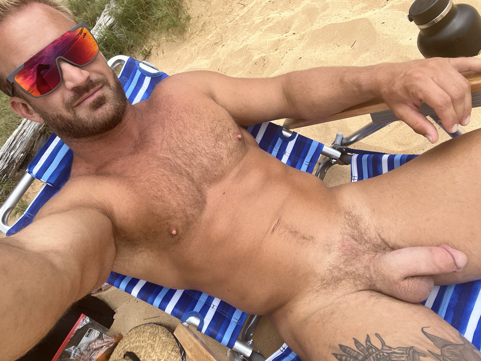 squirt studios star bruce jones sitting naked in a beach chair on a gay male vacation