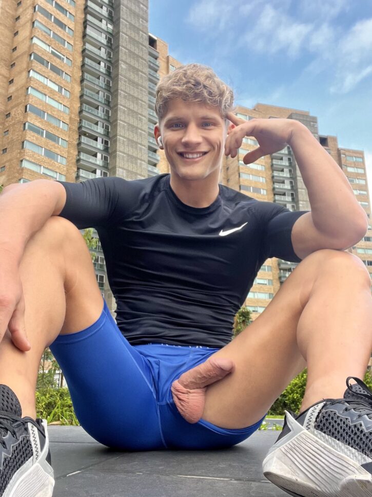 daniel knight smiling to the camera in workout gear with his gay dick hanging out of his blue bicycle shorts