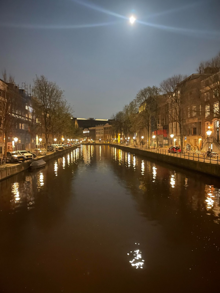 Canals of Amsterdam late at night lit by streetlights and parked cars