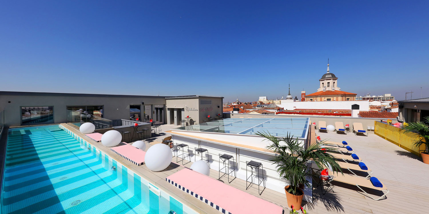 sky bar axel hotel in madrid with view of lounge chairs rooftop pool and skyline via Axel Hotel