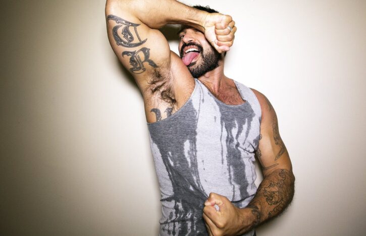 rogan richards wearing a sweaty grey tank top while sticking out his tongue to the camera and showing off hia gay armpit for fetish males