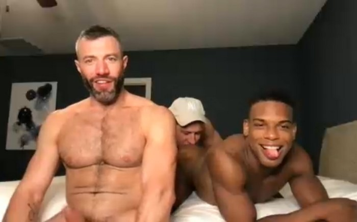 three gay naked males sitting on the bed for a gay sex webcam show while one naked male rims a hot black male twink