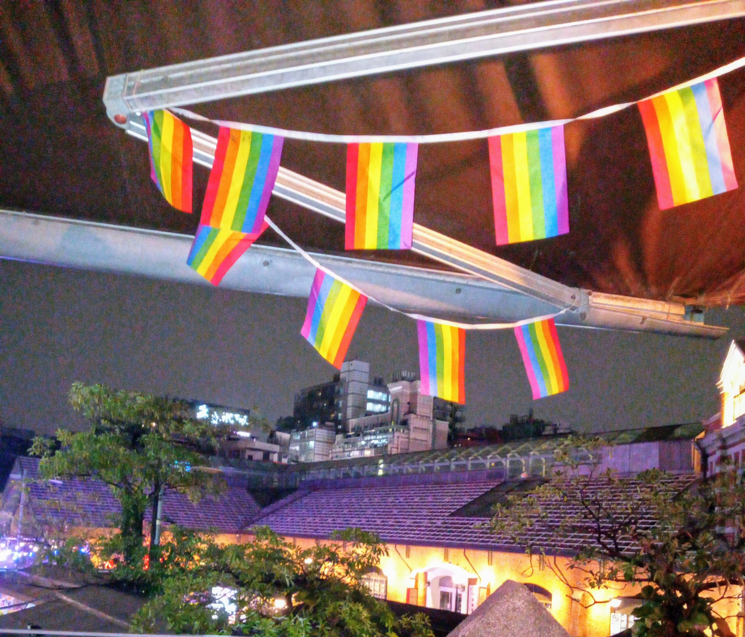 gay LGBTQ flags hanging from the ceiling of taiwanese tavern over night sky