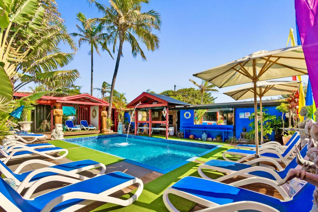 back pool area with lounge chairs and colorful umbrellas for Hideaway Noosa gay mens only resort in sunshine coast australia photo via booking.com