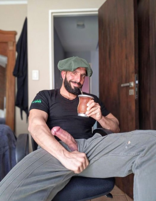 Bulltovich wearing a green beret drinking from a mug with his massive hard cut dick peeking out of his grey slacks