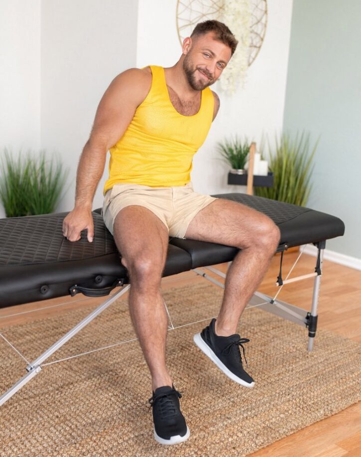 gay xxx gay porn actor Scott Braun posing in yellow tank top and white shorts on a massage table in seancody.com gay xxx porn studio promo photo