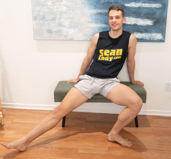 Sam Holister posing on a bench in seancody.com tank top and grey sweatpants showing off his gay penis bulge in gay xxx porn studio promo photo