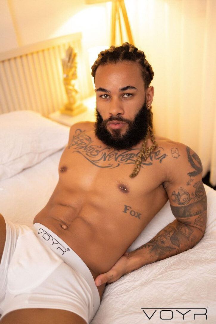 hot gay black porn actor Andy Rodrigues lies shirtless on the bed in white boxer briefs in sexy solo porn image from gay xxx studio voyr