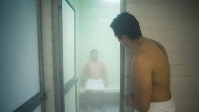 gay male sitting in gay mexico city bathhouse banos rocio while hot naked male gay cruises in the doorway via time out magazine photograph by Alejandra Carbajal