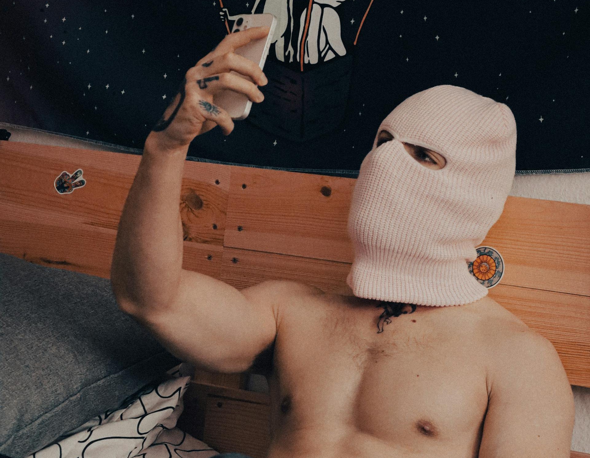 shirtless gay male in pink ski mask hiding his identity browsing gay porn via pexel