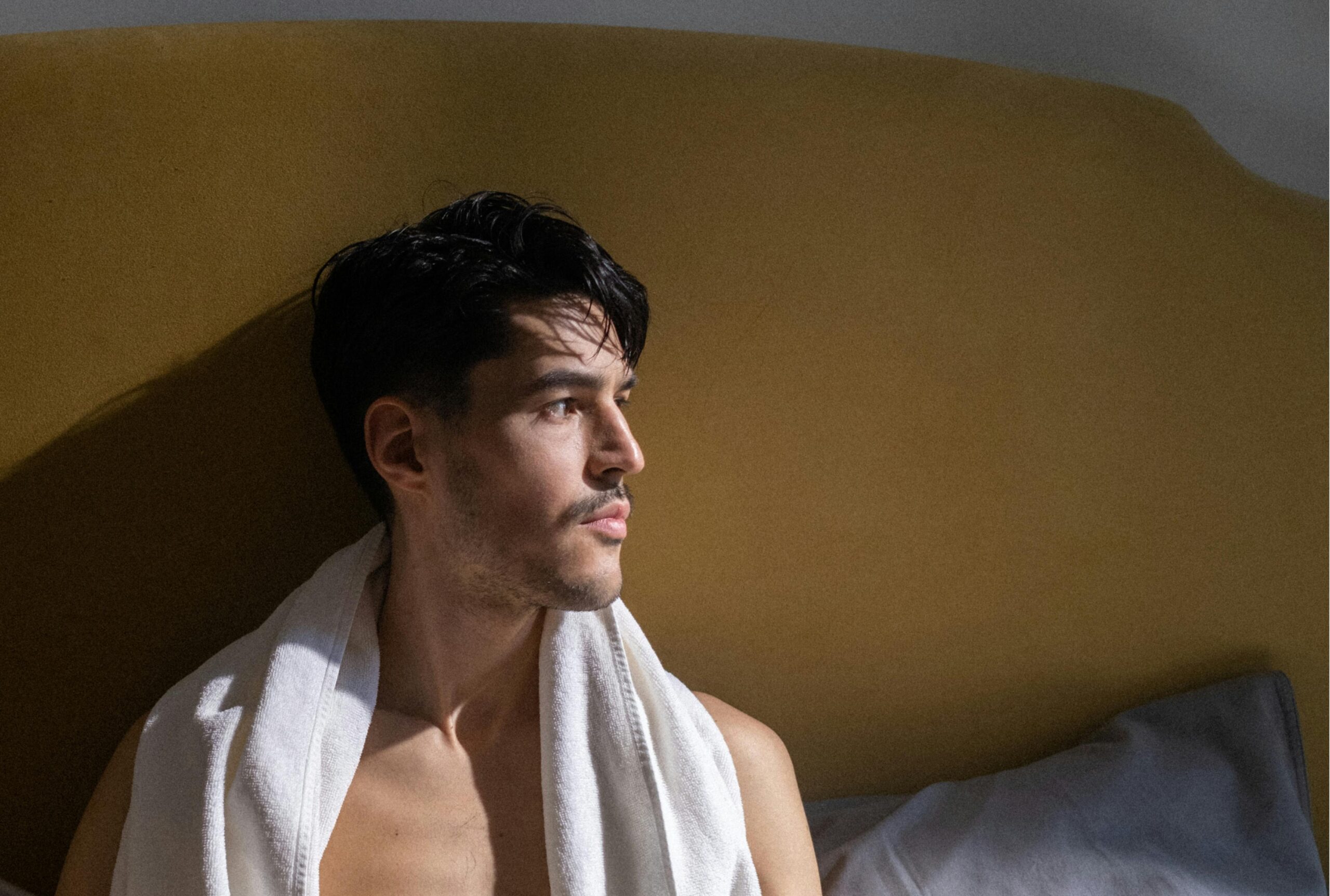 gay male sitting in bed looking out the window contemplating abstinence while participating in no nut november 2025 photo via Ron Latch Pexels