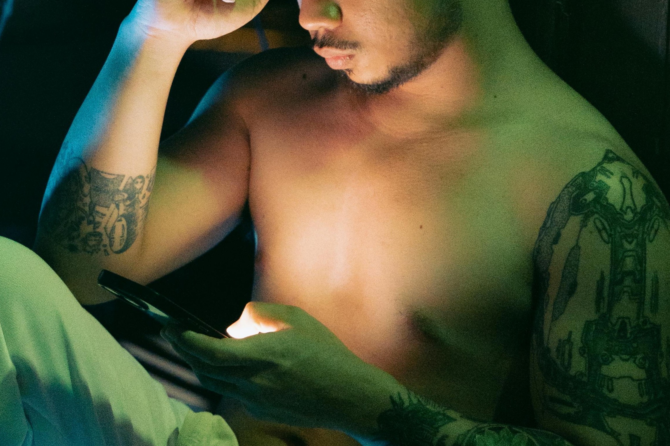 gay shirtless male browsing his gay hookup apps on his phone late at night ready to host gay sex via Kenneth Surillo via Pexels