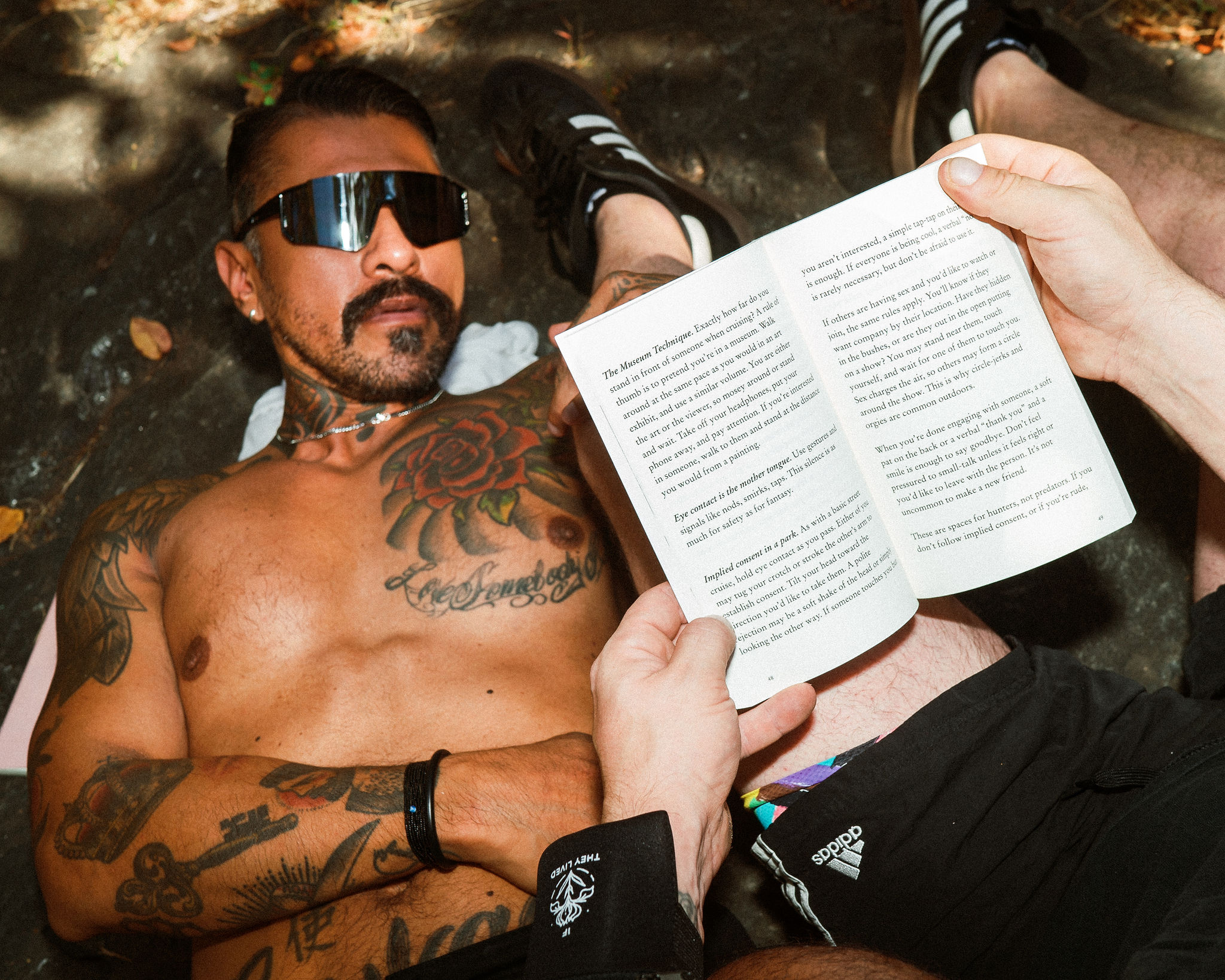 gay cruising analog cruising book by leo herrera sexy tattooed daddy reading book while outdoor park cruising photo by Roland Fitz